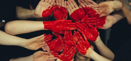 hands formed together with red heart paint