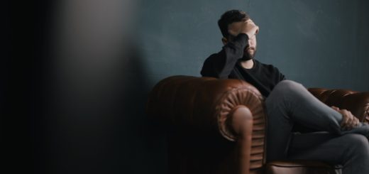 a man holds his head while sitting on a sofa