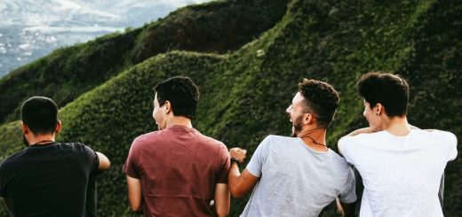 row of four men sitting on mountain trail