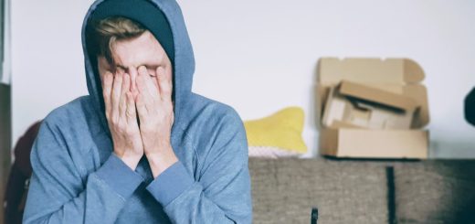 man covering face with both hands while sitting on bench