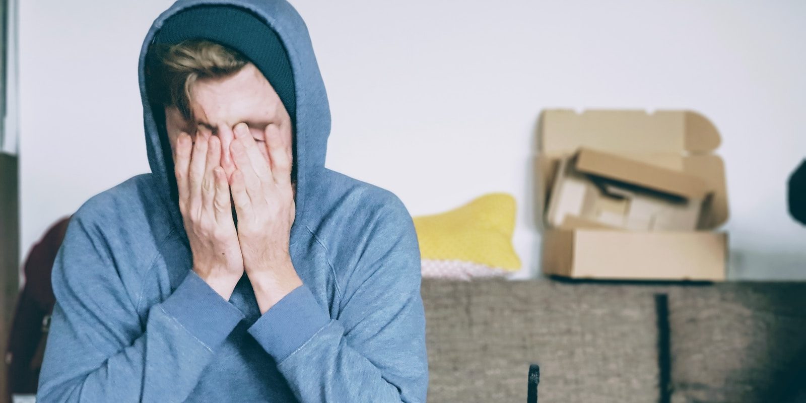 man covering face with both hands while sitting on bench